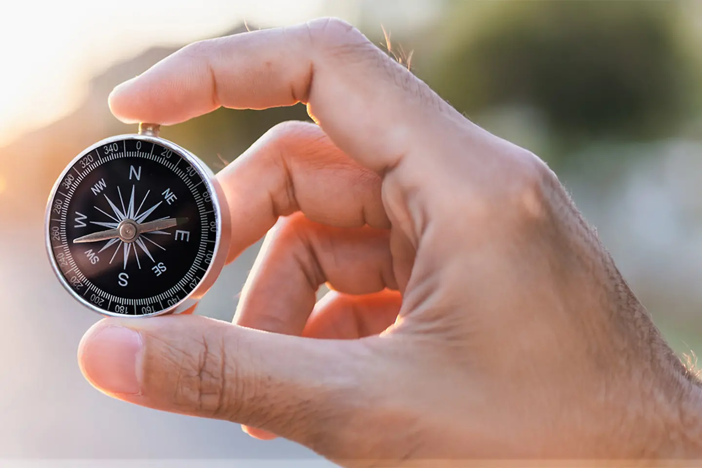 A man holding a compass on blurred background